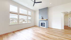 Living room featuring a ceiling fan, a large fireplace, light wood-style flooring, and recessed lighting