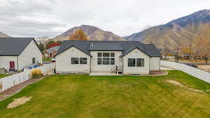 Rear view of house with a mountain view, a fenced backyard, and a patio