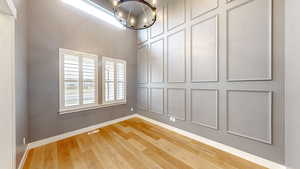 Office with chandelier, plenty of natural light, a towering ceiling, light flooring, and a decorative wall.