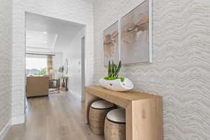Hall featuring wallpapered walls, an accent wall, and light wood-style floors