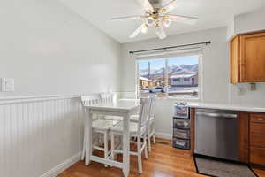 Dining space with a mountain view, light wood-style flooring, a wainscoted wall, and ceiling fan