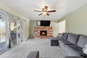 Living room featuring carpet, a fireplace, and ceiling fan