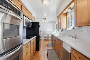 Kitchen featuring appliances with stainless steel finishes, light countertops, light wood-type flooring, and ceiling fan