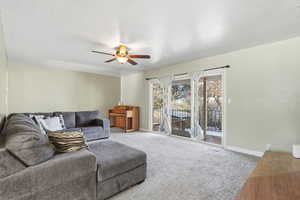 Carpeted living area featuring baseboards and ceiling fan