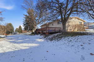 Snow covered rear of property with a wooden deck