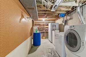 Washroom with unfinished concrete floors and washing machine and dryer