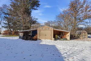 Snow covered structure with a pole building and a storage shed