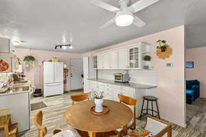 Kitchen featuring light stone counters, a textured ceiling, white appliances, decorative backsplash, and wood tiled floors