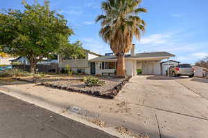 Tri-level home featuring concrete driveway, a chimney, brick siding, a shingled roof, and a carport