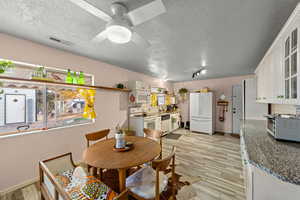 Dining room with a textured ceiling, light wood-style floors, and ceiling fan