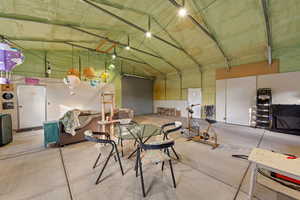 Miscellaneous room with high vaulted ceiling, concrete flooring, and a garage