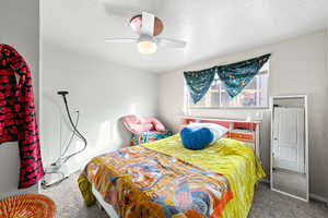 Carpeted bedroom with a ceiling fan