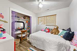 Bedroom featuring a closet, a textured ceiling, wood finished floors, and a ceiling fan