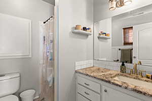 Bathroom featuring a shower with curtain, vanity, and a textured wall