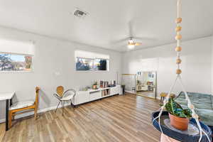Sitting room featuring light wood-style floors, plenty of natural light, and a ceiling fan