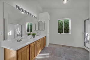 Full bathroom with a shower stall, double vanity, and vaulted ceiling