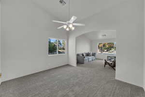 Living area with light colored carpet, high vaulted ceiling, and a ceiling fan