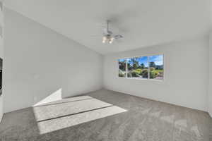 Empty room with carpet, ceiling fan, and lofted ceiling