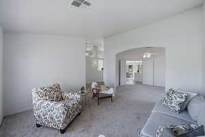Living area featuring carpet floors, arched walkways, a ceiling fan, and lofted ceiling