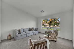 Carpeted living room featuring lofted ceiling and baseboards