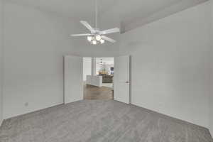 Unfurnished room with high vaulted ceiling, light carpet, and a ceiling fan