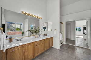 Full bath featuring a stall shower, double vanity, a bathtub, healthy amount of natural light, and a high ceiling