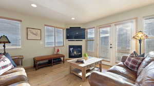 Living room featuring light wood-type flooring, a glass covered fireplace, plenty of natural light, and recessed lighting