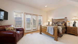 Bedroom with access to exterior, lofted ceiling, recessed lighting, and light colored carpet