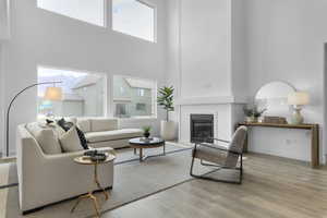 Living area with a high ceiling, a glass covered fireplace, light wood-style flooring, and healthy amount of natural light