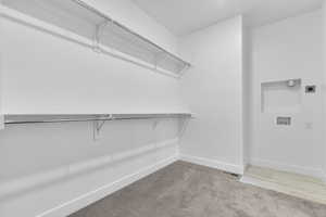 Walk in closet with light colored carpet
