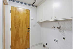 Laundry room with cabinet space and wallpapered walls