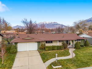 Ranch-style home featuring a mountain view, a front yard, driveway, and an attached garage