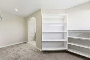 Spacious closet featuring light colored carpet and arched walkways.  Off Primary suite Bathroom