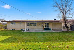 Rear view of property with a patio, brick siding, and a yard