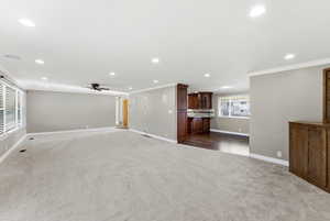 Unfurnished living room featuring dark carpet, recessed lighting, crown molding, and a ceiling fan