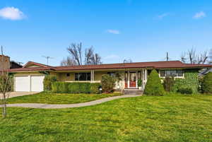 Ranch-style house with a front lawn, an attached garage, concrete driveway, and brick siding