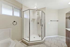 Full bathroom with light tile patterned floors, a shower stall, and a bath, double sink around corner and large closet