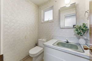 Half bathroom featuring vanity and wallpapered walls