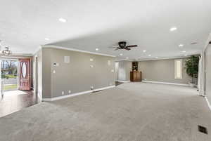 Unfurnished living room featuring healthy amount of natural light, light colored carpet, recessed lighting, crown molding, and a textured ceiling