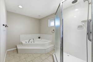 Bathroom featuring a garden tub, a stall shower, and light tile patterned floors, double sinks in this primary bathroom and a huge closet