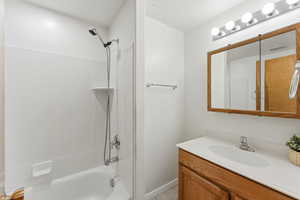 Bathroom with shower / bathtub combination, vanity, and light tile patterned floors.