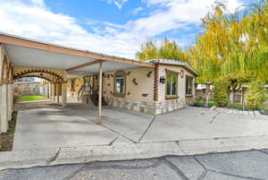 View of side of property featuring a carport, concrete driveway, and a gate