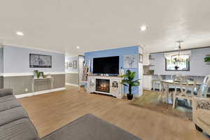 Living area with light wood-style flooring, recessed lighting, a chandelier, wood walls, and a wainscoted wall
