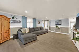 Living area featuring wainscoting, crown molding, light wood-style flooring, and recessed lighting