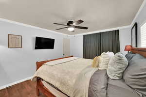 Bedroom with wood finished floors, a ceiling fan, and ornamental molding