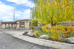 View of front of house featuring a carport, a fenced front yard, stucco siding, concrete driveway, and stone siding