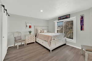 Bedroom featuring a barn door, light wood finished floors, and recessed lighting
