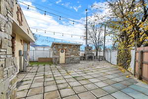 Fenced backyard with a patio area and an outdoor stone fireplace