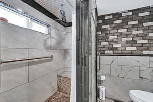 Bathroom featuring a shower stall and tile walls
