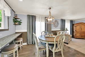 Dining space with healthy amount of natural light, wood finish floors, a chandelier, and crown molding